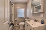 The chic full bathroom features a glass-enclosed shower/tub combo